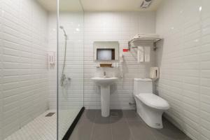 a white toilet sitting next to a white sink in a bathroom at Skyone Hotel in Kaohsiung