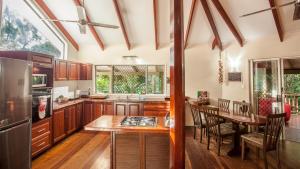 uma cozinha com armários de madeira, uma mesa e uma sala de jantar em Daintree Secrets Rainforest Sanctuary em Diwan