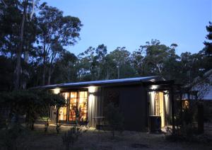 una pequeña casa con luces encendidas en el bosque en Lily's Farm Studio, en Glenlyon