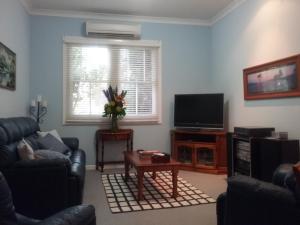 a living room with a couch and a television at Langley Cottage B&B in Coonabarabran