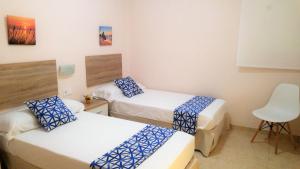 pokój z 2 łóżkami i krzesłem w obiekcie Valencia Gold Beach w Walencji