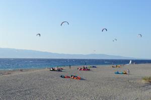 a group of people on a beach flying kites at La punta dei venti in Pellaro