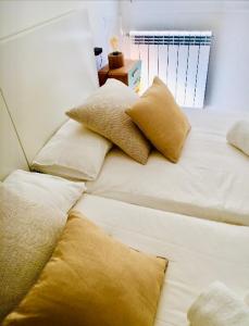 Una cama blanca con almohadas encima. en Zurriola Beach, en San Sebastián