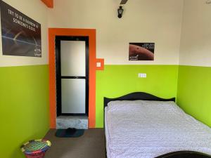 1 dormitorio con paredes de color verde y naranja y 1 cama en Om sweet Home ॐ, en Pokhara