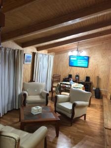 a living room with chairs and a tv on the wall at Departamento Amoblado in Concepción