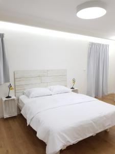 um quarto branco com uma cama grande e lençóis brancos em Stylish Apartment with a Patio close to the beach em Eilat