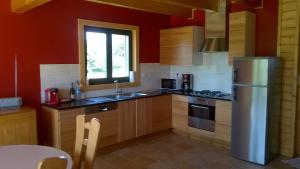 a kitchen with red walls and wooden cabinets and a refrigerator at Entre Paimpol et Bréhat ! in Ploubazlanec