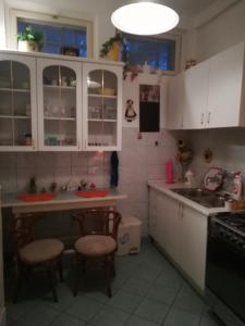 una cocina con armarios blancos y 2 taburetes. en Violetta apartmanlakás en Hévíz