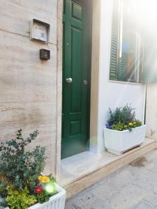 eine grüne Tür an der Seite eines Hauses mit Pflanzen in der Unterkunft apartment rent Casa ALMIKA in Bari