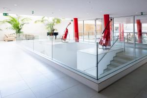 a glass lobby with stairs and red columns at Hotel da Música in Porto +44 photos