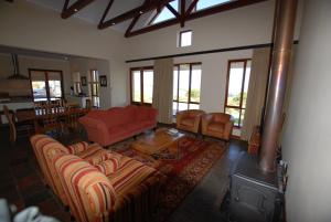 un soggiorno con un divano rosso e un camino di Kingsbury Cottage a Breërivier