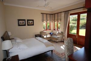 una camera da letto con un grande letto bianco e una sedia di Kingsbury Cottage a Breërivier