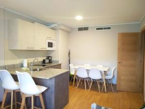 a kitchen with white chairs and a counter top at Apartamentos Prestin in Cangas de Onís