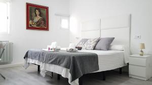 a white bedroom with a bed and a painting at Casa Botes in Cuenca