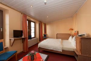 a hotel room with a bed and a television at Logis Hotel-Restaurant Petry in Vianden