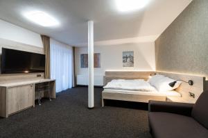 a bedroom with a bed and a tv and a couch at Penzion Pod Kartouzkou in Dolany