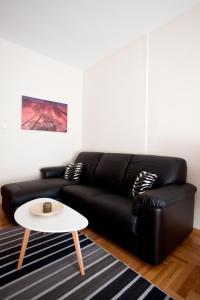 un sofá de cuero negro con una mesa blanca en la sala de estar en New Stylish and Cozy House, en Tesalónica