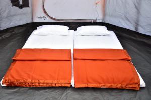 ein orangefarbenes und weißes Bett in einem Zelt in der Unterkunft Bombay Camping Company in Lonavla