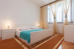 ein weißes Schlafzimmer mit einem Bett und zwei Fenstern in der Unterkunft Apartman Orange in Podgora