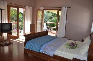 a bedroom with a bed and a television and a balcony at serin du cap in Blue Bay