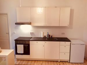 a small kitchen with white cabinets and a sink at Modernes Apartment am Viktoria Luise Platz in Berlin