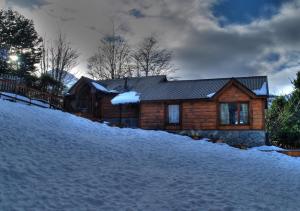 a log cabin with snow in front of it at Aves del Sur in Ushuaia +14 photos