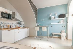a kitchen with white cabinets and a blue wall at Miramare love nest 5terreparco in Riomaggiore