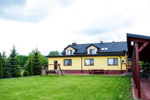 una casa amarilla con parque infantil en el patio en Nad Bugiem, en Hrubieszów