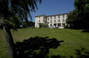 a building with a tree in front of a grass field at Hotel Le Bellevue in Wissant