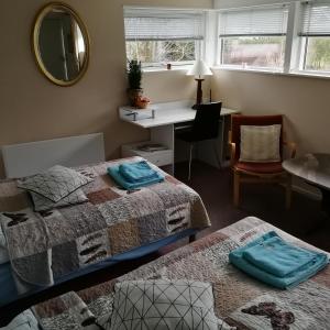 een slaapkamer met 2 bedden, een bureau en een spiegel bij Risskov Bellevue Guesthouse in Aarhus