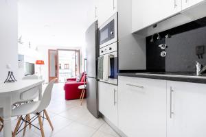 a kitchen with white cabinets and a white table at Apartamento 1º de Maio in Tavira