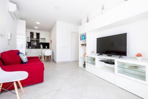 ein Wohnzimmer mit einem roten Sofa und einem Flachbild-TV in der Unterkunft Apartamento 1º de Maio in Tavira