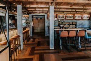 a restaurant with wooden floors and tables and stools at Hotel De4dames in Schiermonnikoog