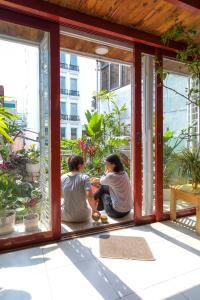 dos personas sentadas en un porche mirando por la ventana en Hanoi Secret Garden en Hanói