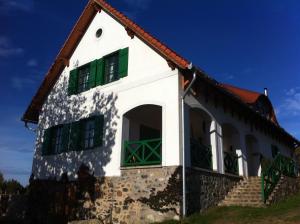 a white house with green windows and a red roof at Kolonics Pincészet Vendégház Somló in Somlóvásárhely