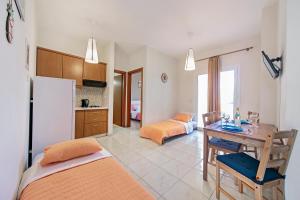 a kitchen and living room with a table and a refrigerator at Omega Comfy Apartments Almyrida in Almyrida