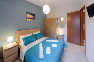 a bedroom with a blue bed with two towels on it at Omega Comfy Apartments Almyrida in Almyrida