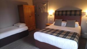 a hotel room with two beds and two lamps at Benleva Hotel in Drumnadrochit