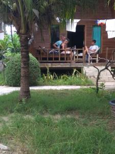 two people sitting on a porch of a house at II Bungalow in Gili Meno