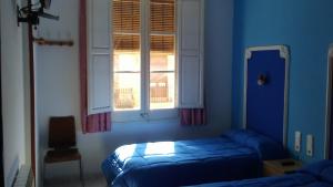 サン・ボイ・ダ・リュブラガートにあるHostal Porta de Ferroの青いベッドルーム(ベッド1台、窓付)