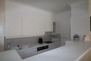 a kitchen with white cabinets and a sink at Noble dune in Oostduinkerke
