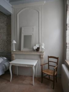 een slaapkamer met een tafel, een stoel en een spiegel bij Le Logis XVIIème in Moulins