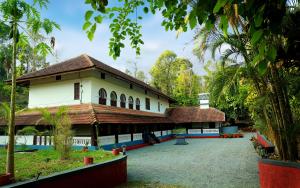 a building in the middle of a park with trees at Keloth Tharavadu in Panamaram