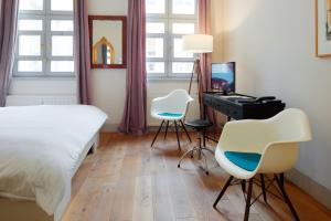 a bedroom with two chairs and a bed and a television at Hotel Fregehaus in Leipzig