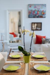 a dining room table with plates and a vase with flowers at Les Gîtes de Claire in Honfleur