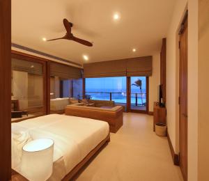 a bedroom with a bed and a living room with a couch at Riff Hikkaduwa in Hikkaduwa
