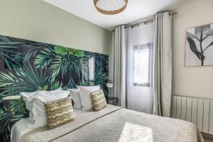 a bedroom with a large bed with a tropical wallpaper at Cottages Domaine du Grand Bec in Villerville