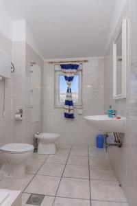 a white bathroom with a toilet and a sink at Apartments Mirjana in Trogir