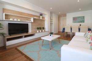 a living room with a television and a white couch at Estación de tren by Como en Casa in Santiago de Compostela