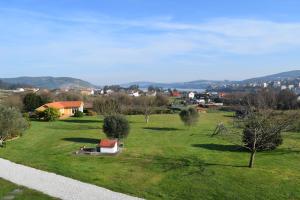 a green field with trees and a town in the background at Casas Cuncheiro in Canduas